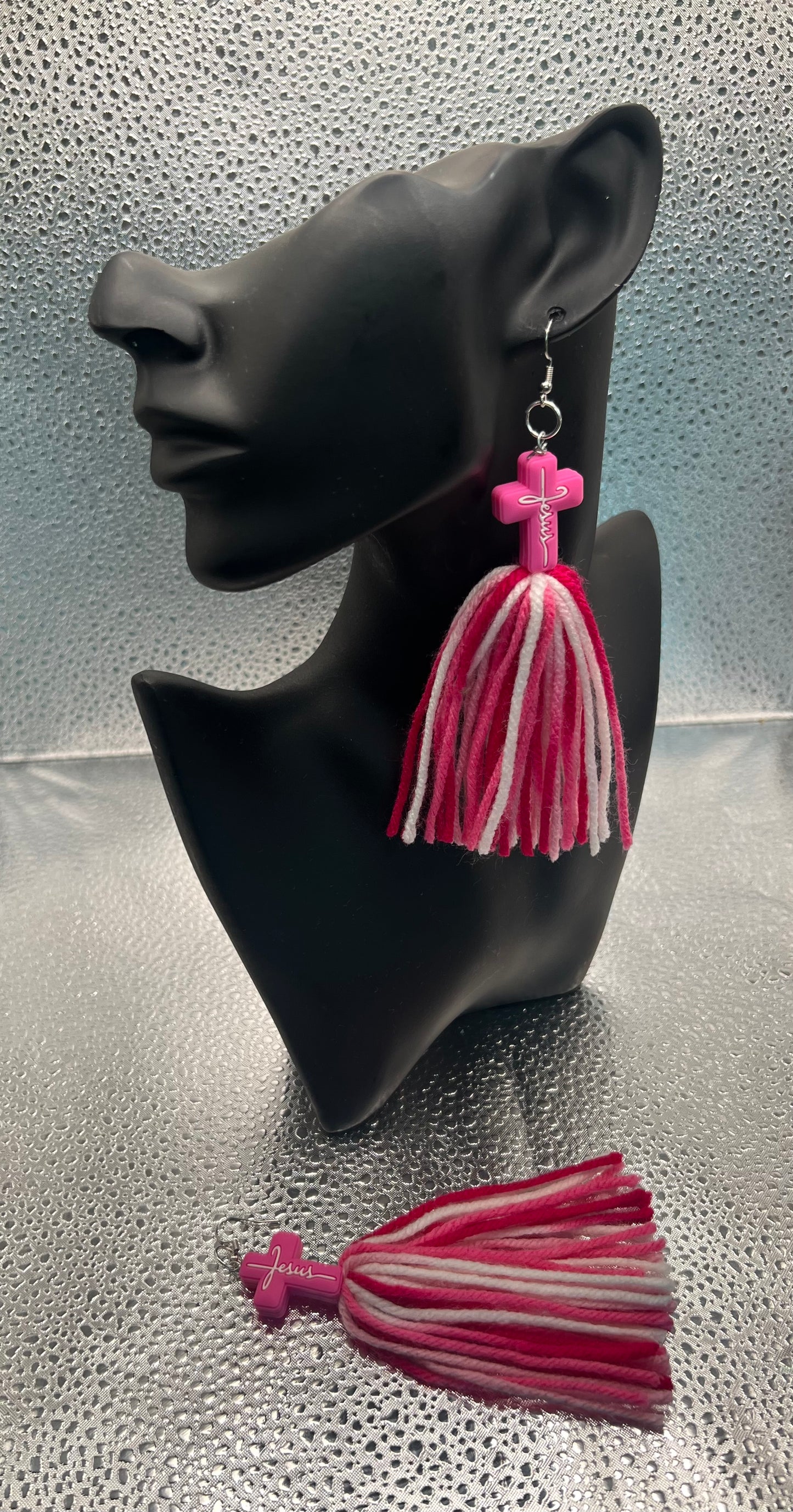 #561-3 Pink cross w/Jesus on it with varies shades of pink & white yarn tassels